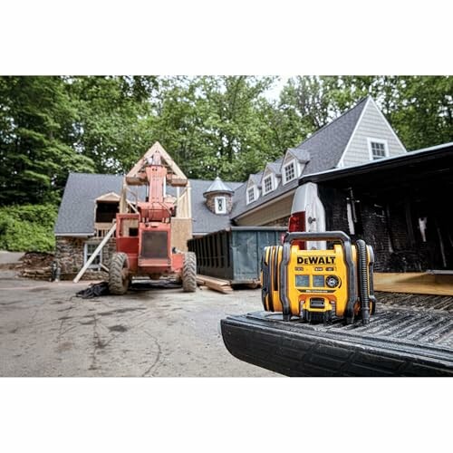 DeWalt speaker on truck bed at construction site with house and machinery.