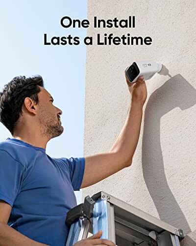 Man installing security camera on wall.