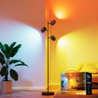Modern floor lamp with adjustable color lights next to a plant and sofa.