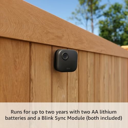 Outdoor security camera mounted on wooden fence.