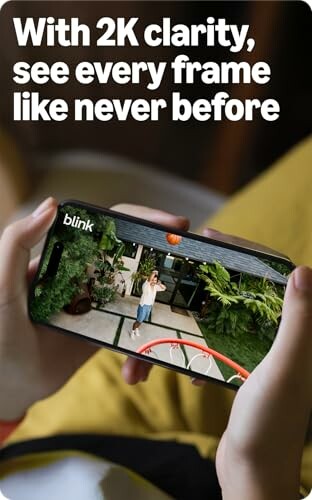 Person holding a phone displaying a basketball shot with text about 2K clarity.