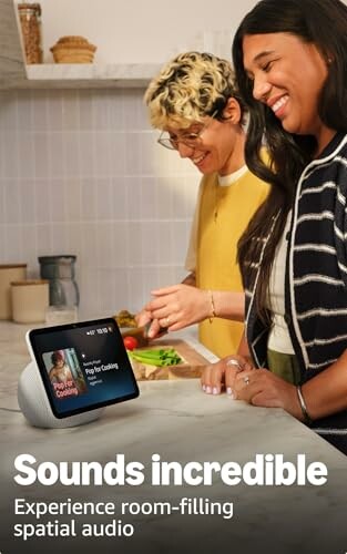 Two people using a smart speaker with screen in a kitchen.